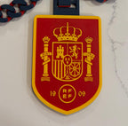 closeup of 3D‑printed españa football team necklace in red, blue, and yellow with chain attachment.
